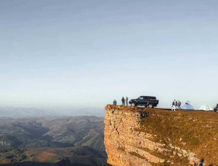 a car is sitting on a cliff overlooking the sky and mountains