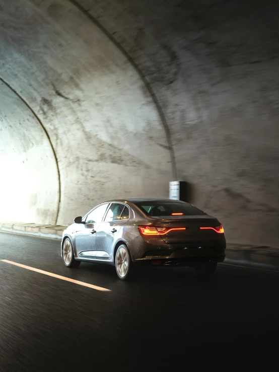 a dark car drives through a tunnel on the highway