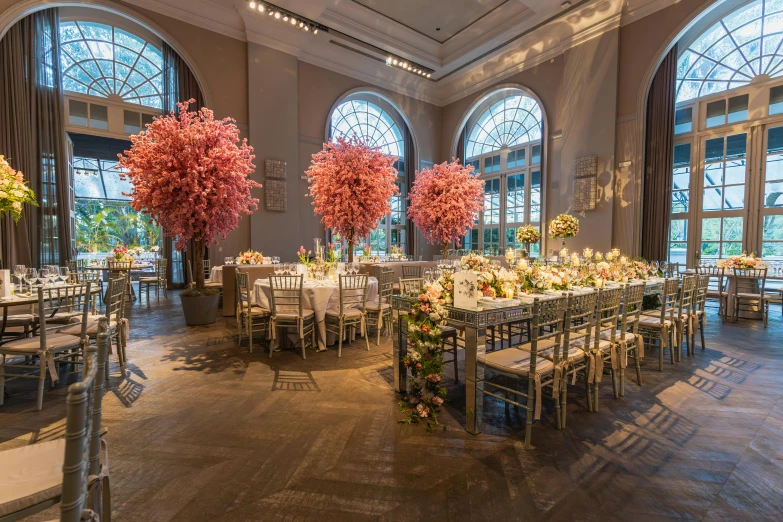 a banquet room with multiple tables and chairs, four large red flowers in the middle