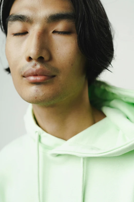a man with black hair and green sweatshirt looks to his right