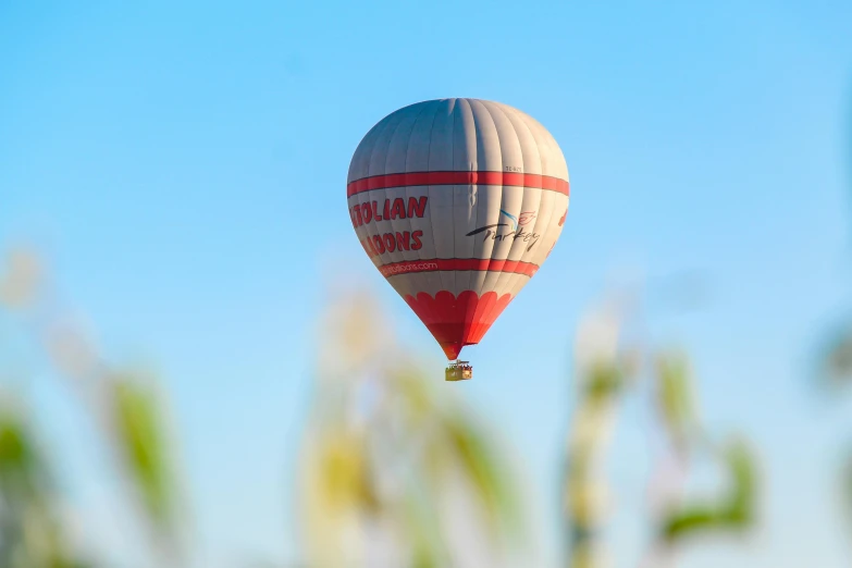 a red and white  air balloon floating through the blue sky