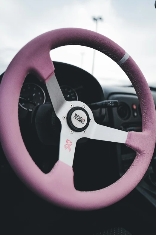 a closeup of the pink and white leather steering wheel cover on a car