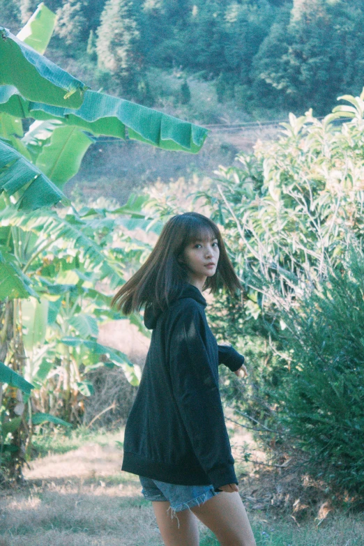 girl riding skate board on grass, in the woods