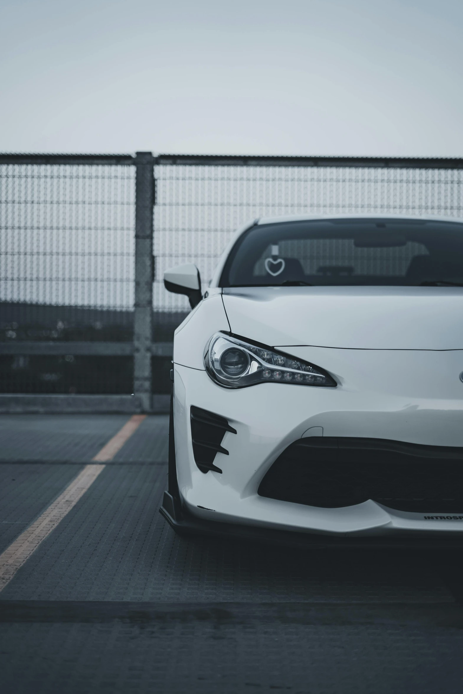 a white toyota sports car sits in front of a fence