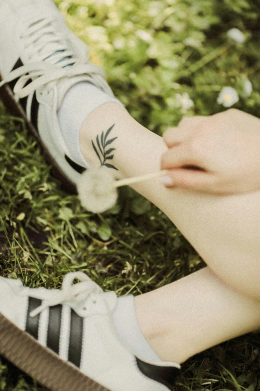 a person wearing adidas shoes and holding a small cigarette