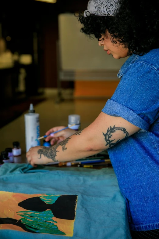 woman sitting with an arm tattoo working on a design
