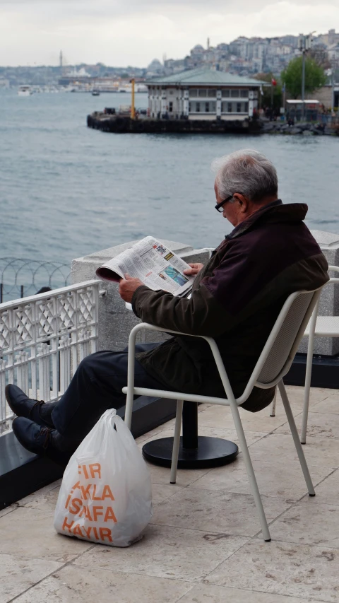 the older man is reading the paper at the bench