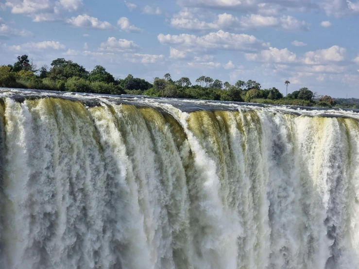 a waterfall with a river running alongside it