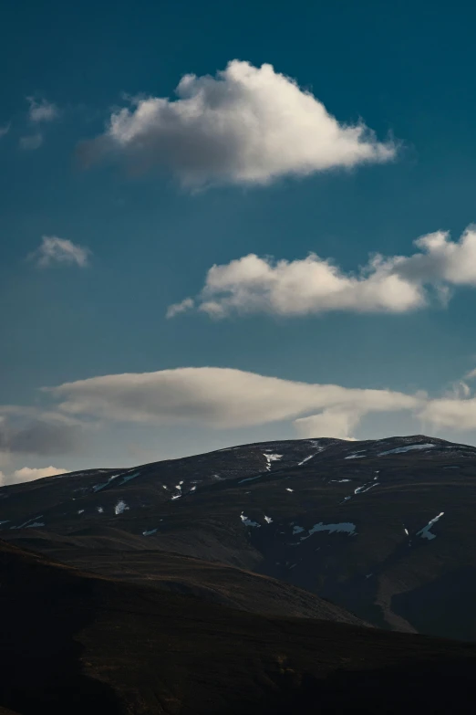 some clouds that are floating on a hill side