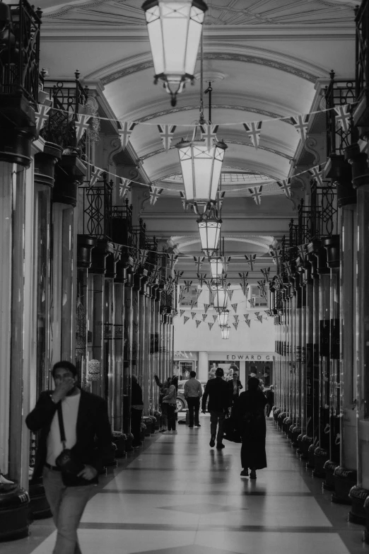 a black and white image of people walking down a hallway