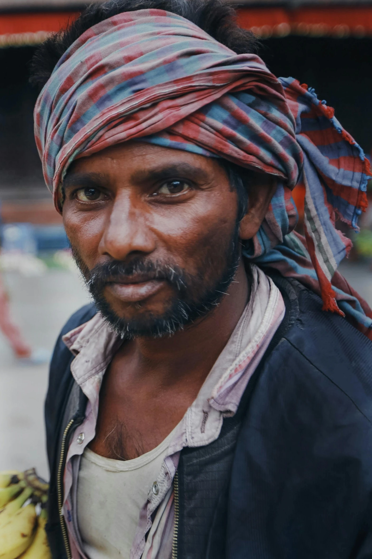 a man wearing a head scarf and a turban looking to the side