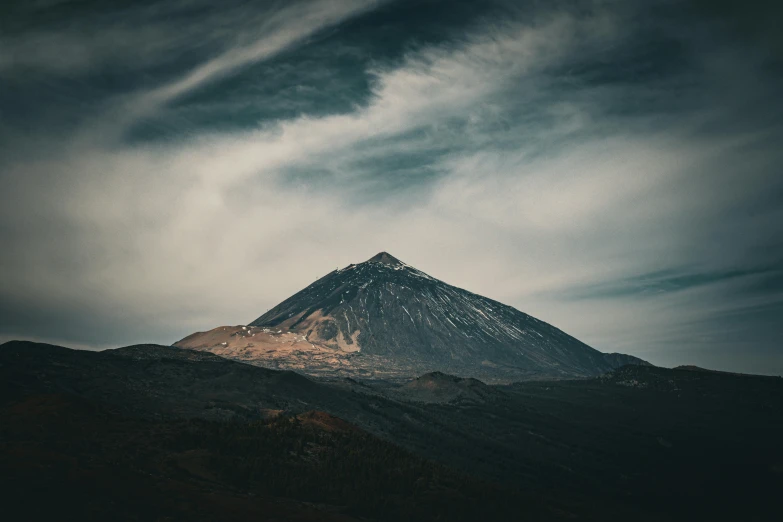 a mountain with a cloud covering it in the evening