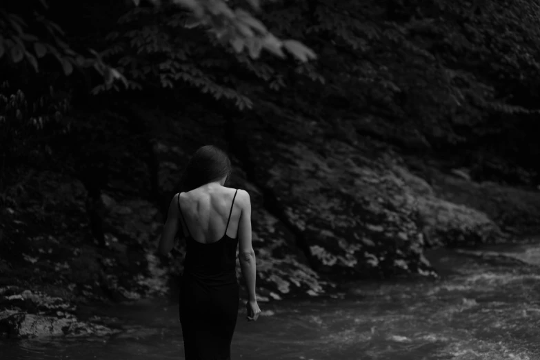 woman in dress standing by body of water