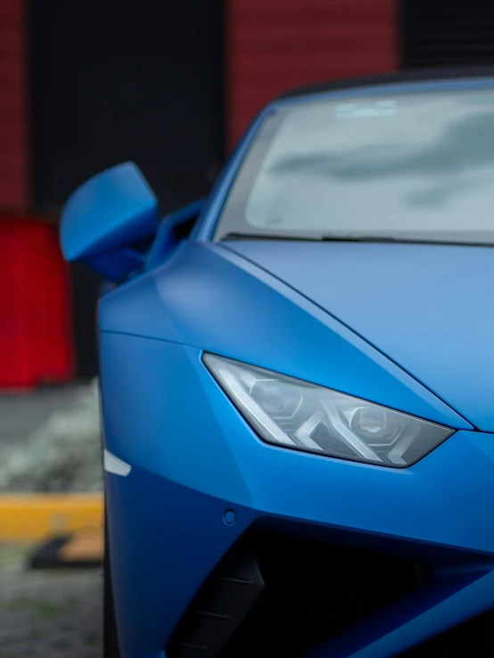 the front end of a blue sports car parked in front of a building