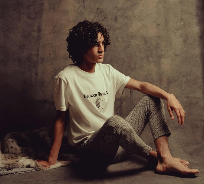 young man sitting on ground in front of fabric