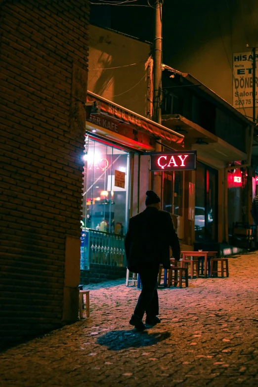 a man in black walks past a building at night