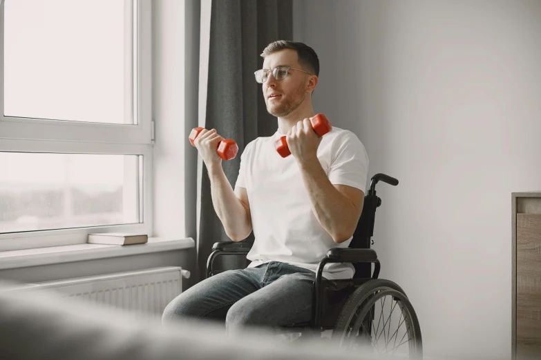 a man with glasses is holding a red dumbbell