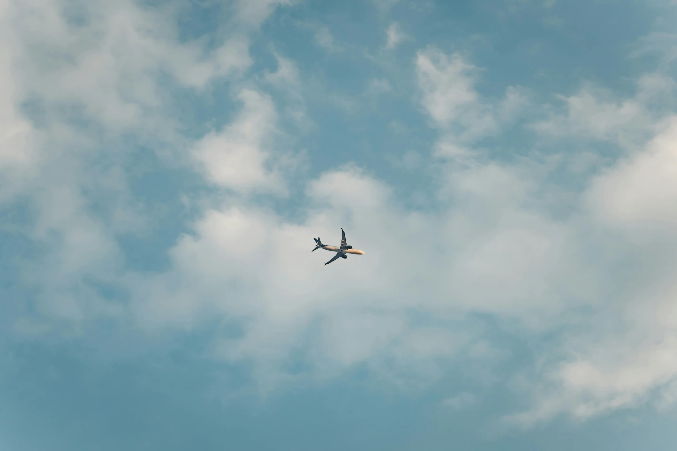 a plane flying through a blue cloudy sky