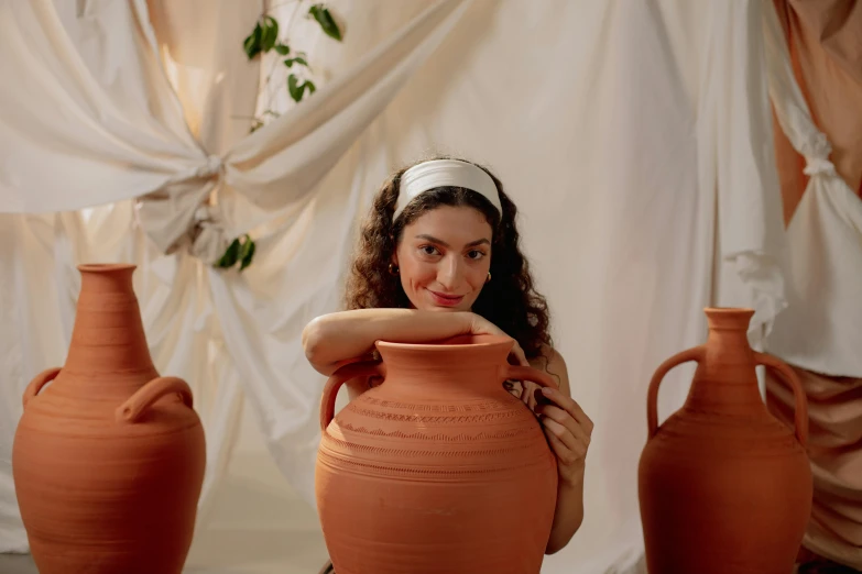 a woman poses next to a bunch of vases