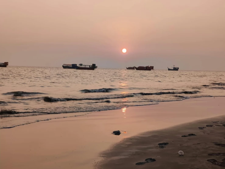 fishing boats at the sea with the sun rising over the horizon