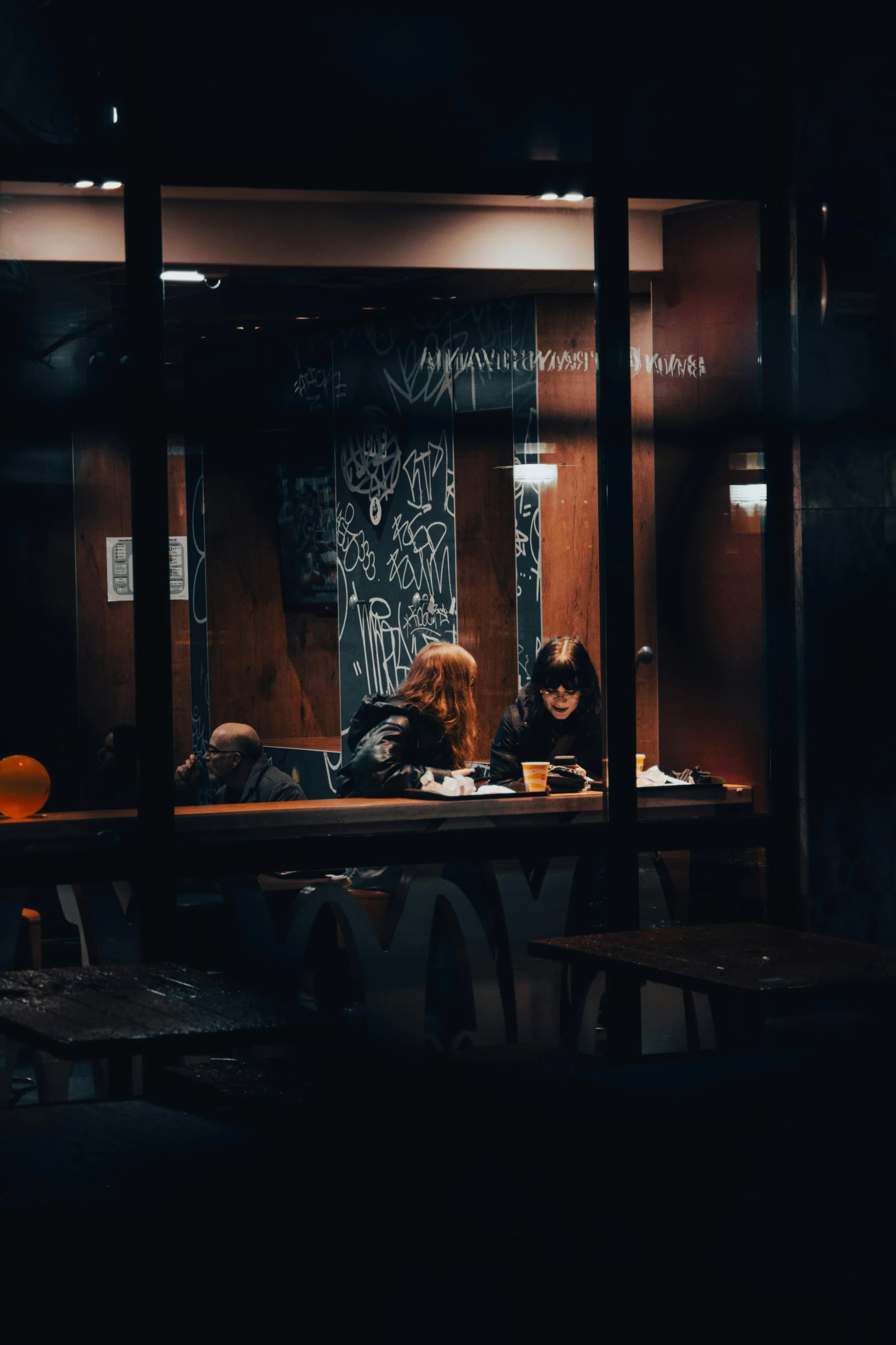 two people are sitting in a dark bar and one is writing soing