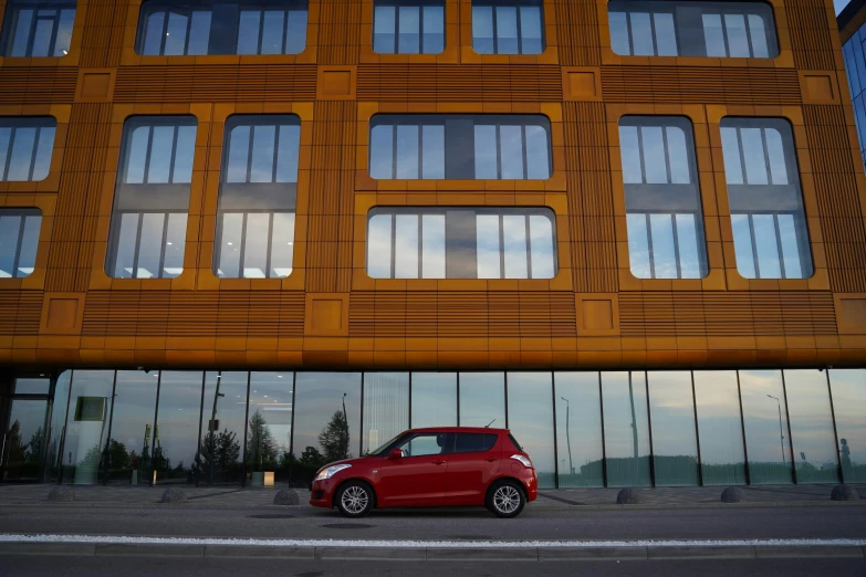 a small red car is parked in front of a building