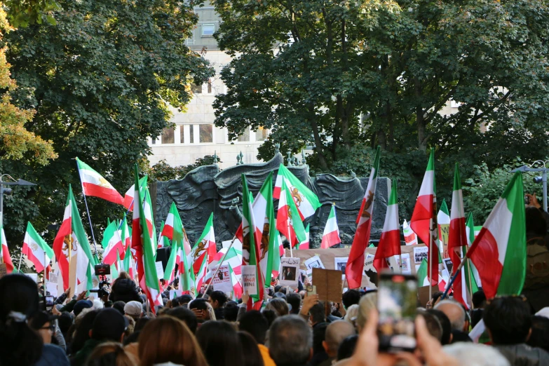 a large group of people holding flags standing in the middle of a street