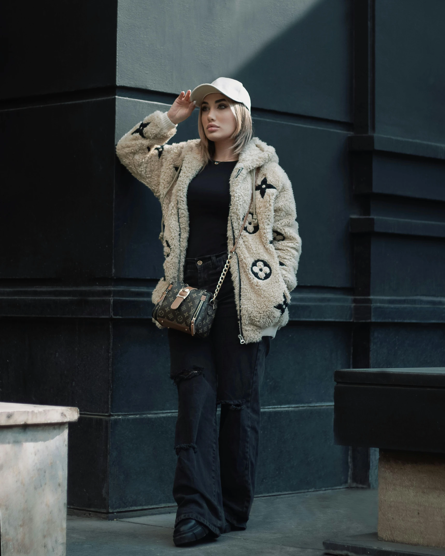 woman wearing black pants and furry coat outside a building