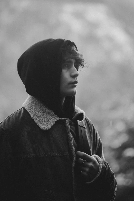 a young man is standing outside in black and white