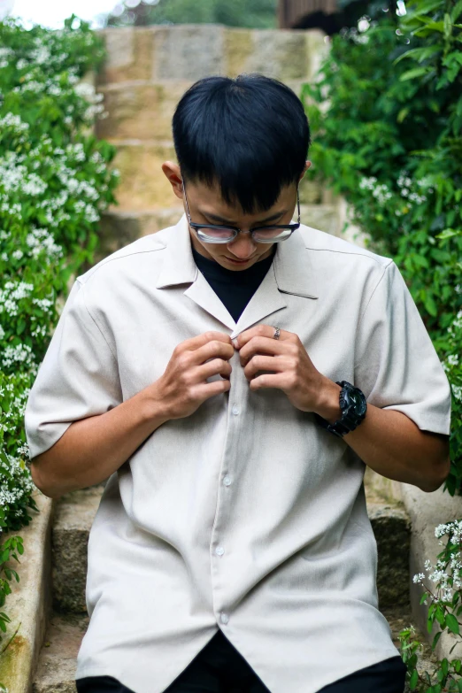 a person holding soing while wearing sunglasses and standing in front of a group of bushes