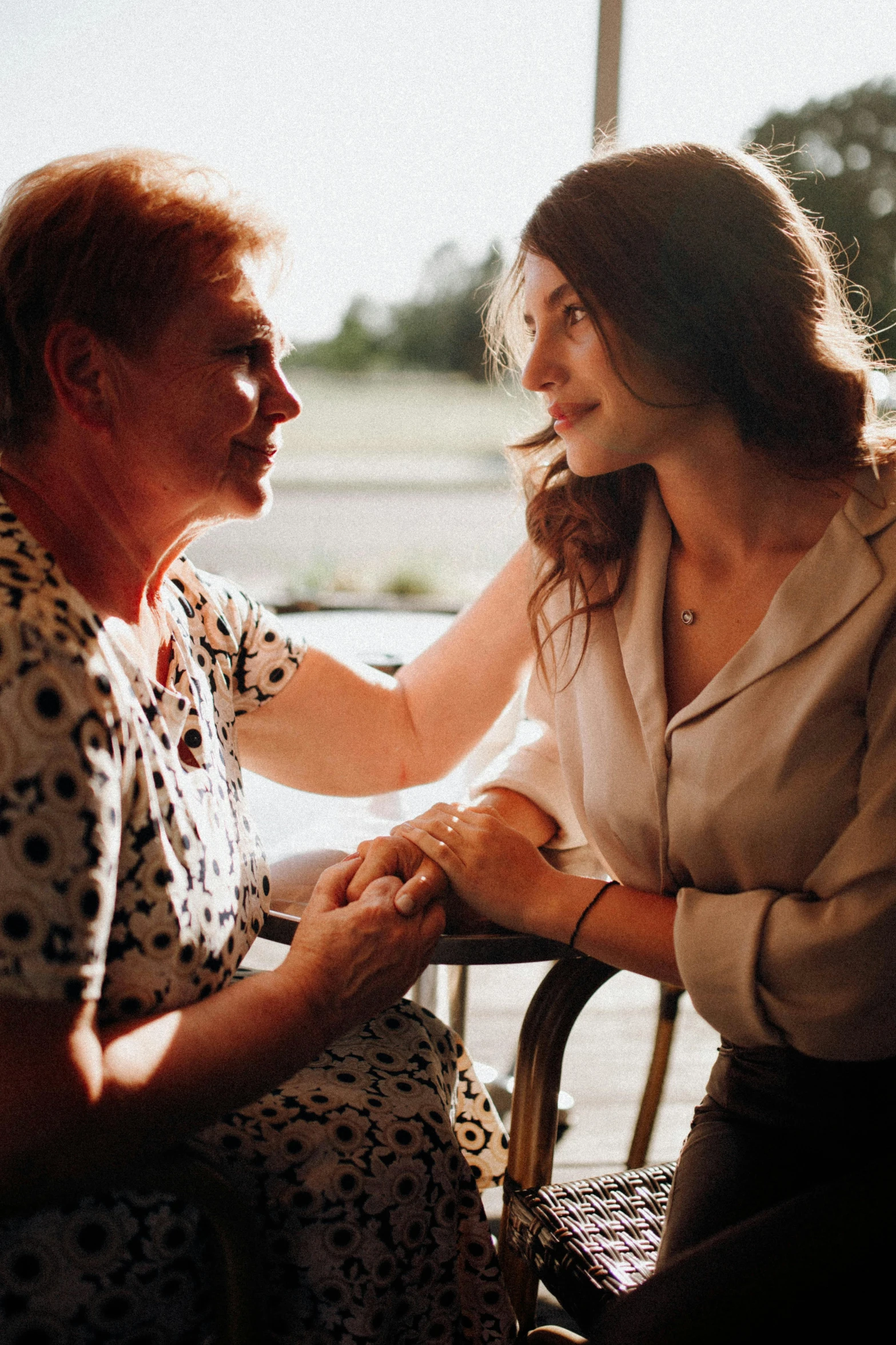 two women sitting down holding hands