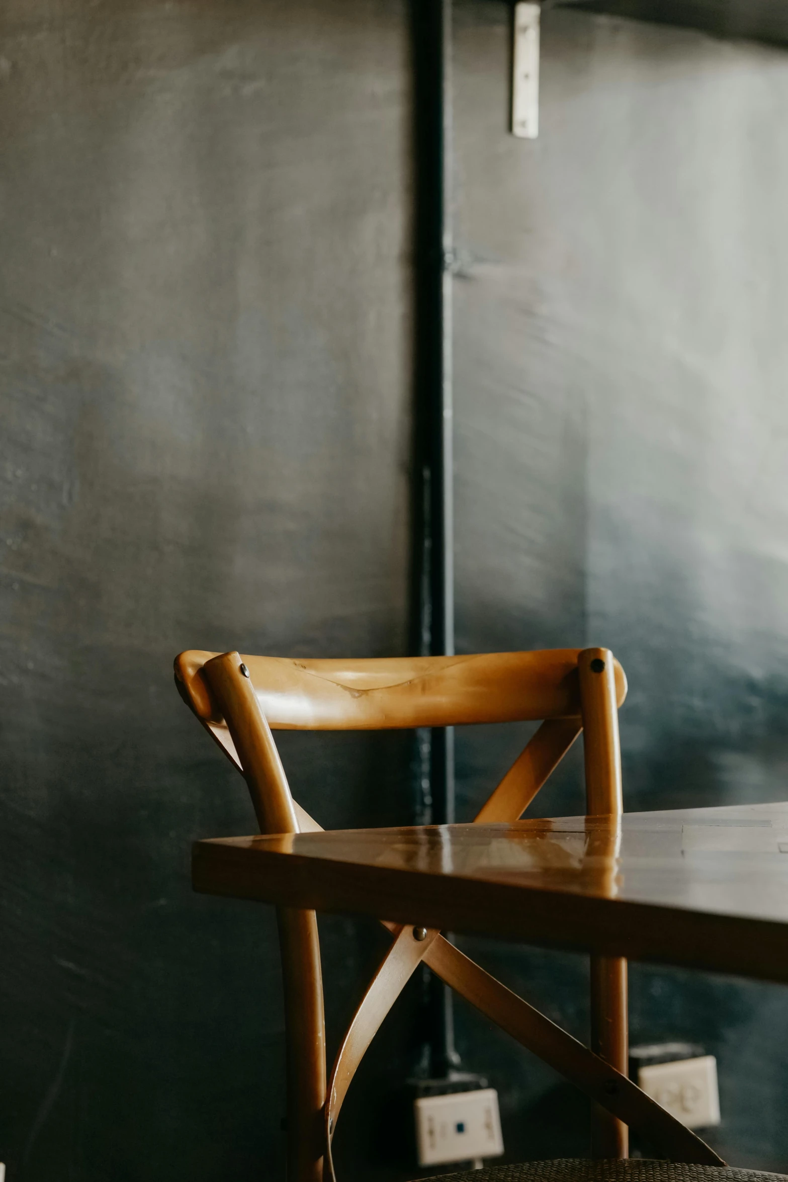 wooden chair in a room next to a black wall