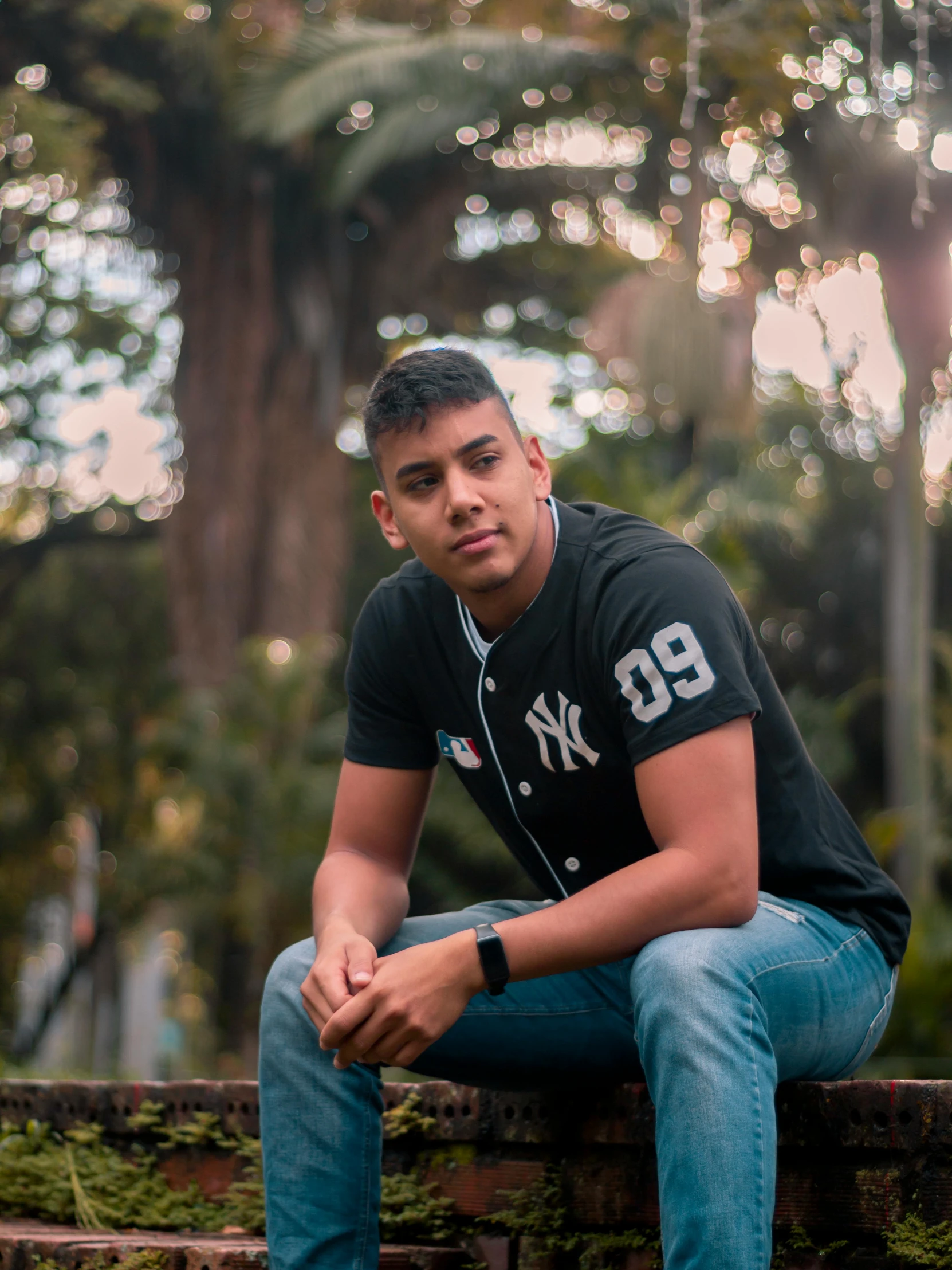 man sits on ledge in front of trees