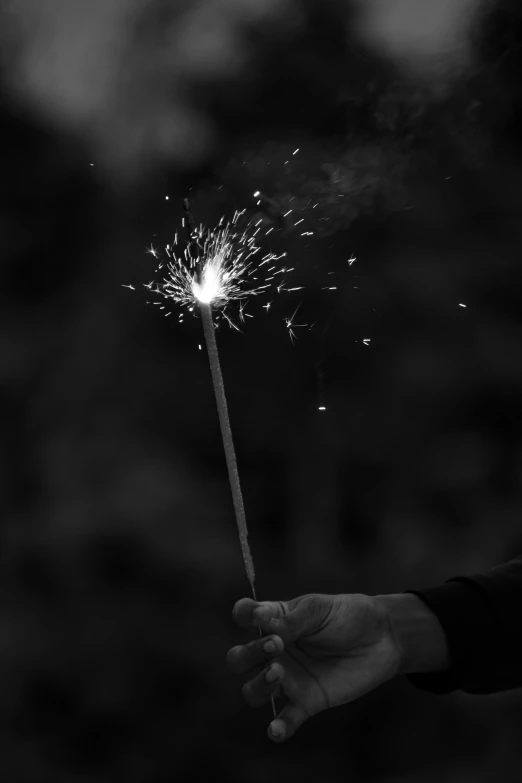 person holding up a lite up sparkler in the dark