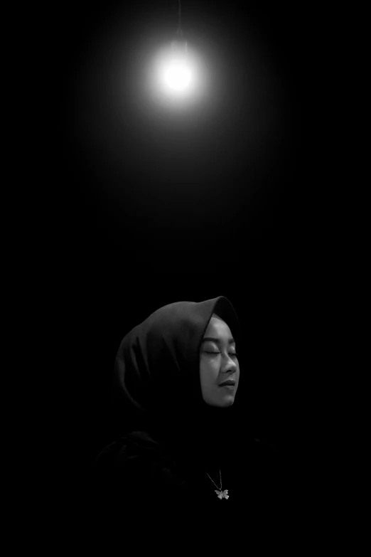 black and white image of a woman sitting in the dark