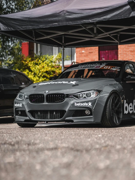 a grey bmw race car is parked in front of a store