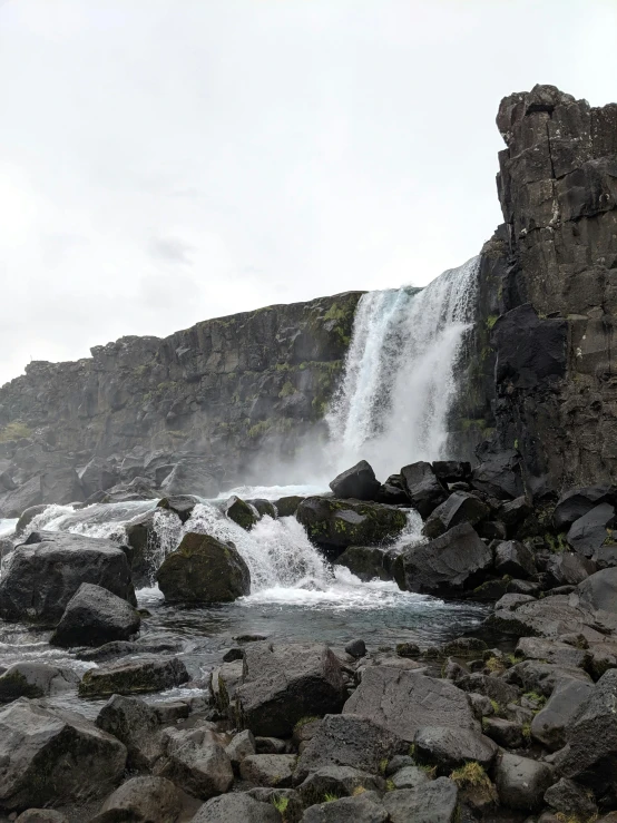 a waterfall with water running over rocks next to it