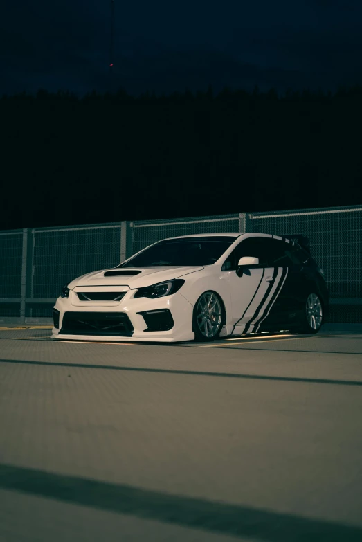 a white car parked in front of a fence