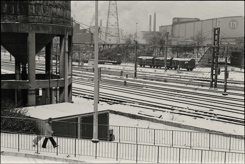 a man walking past a large building near train tracks