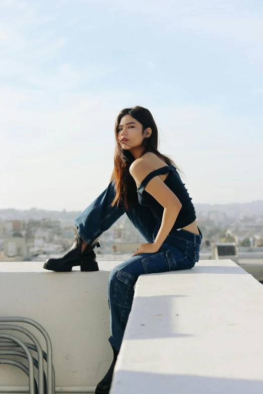 woman in black top sitting on ledge looking at camera