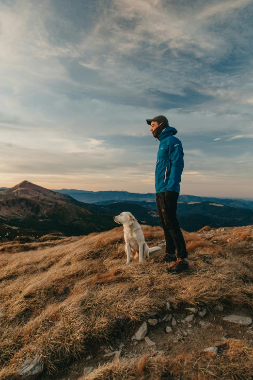 a man standing on top of a mountain with his dog