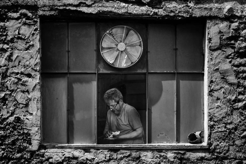 a man is sitting in an old building, while looking out the window