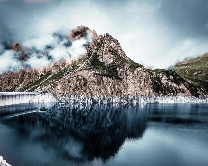 the mountain range is reflected in the still water