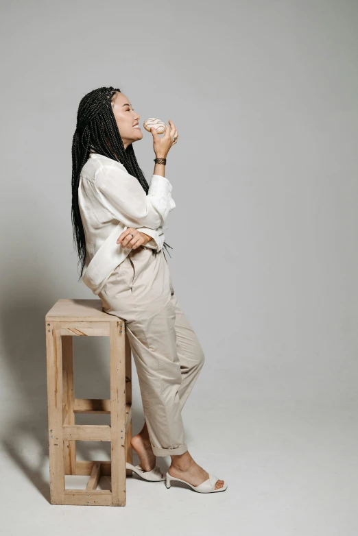 woman sitting on a wooden stool holding a donut