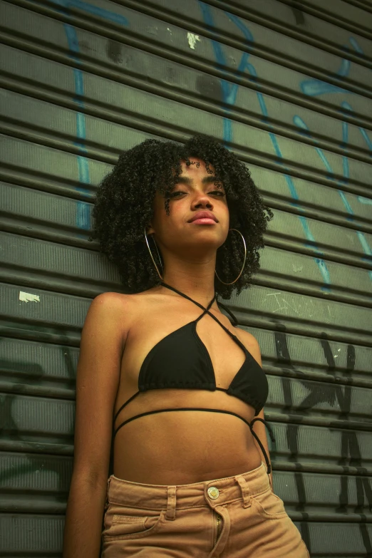 a beautiful young woman wearing a bikini and standing in front of a grungy wall