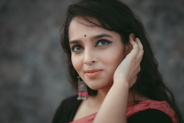 a young woman with long black hair wearing large blue earrings