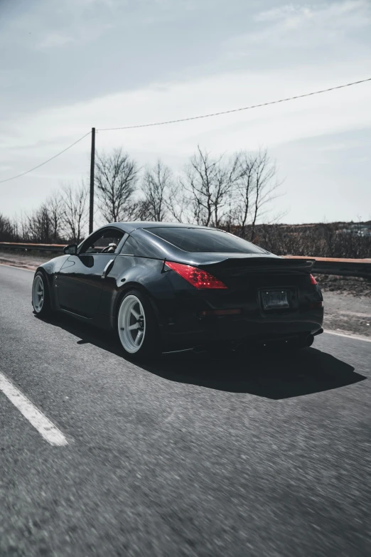 black sports car driving on empty road in the winter