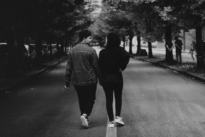 two people walking down the middle of a road