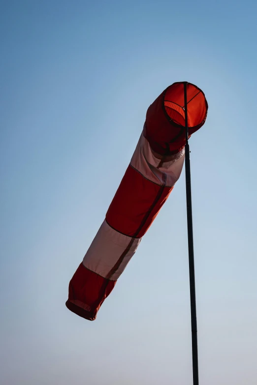 a red and white striped umbrella hanging from a black pole