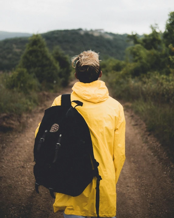 a person in yellow rain coat holding a black backpack